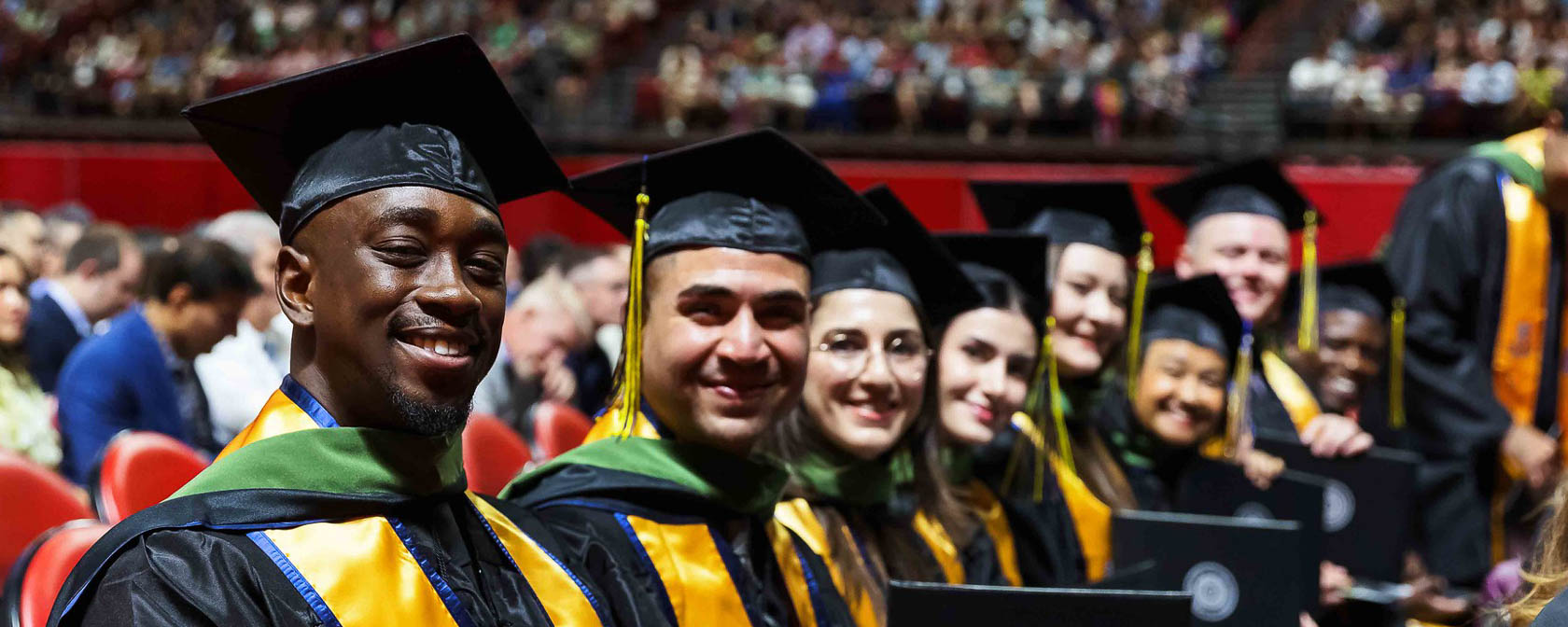 Students in graduation caps gowns sit together during a commencement ceremony