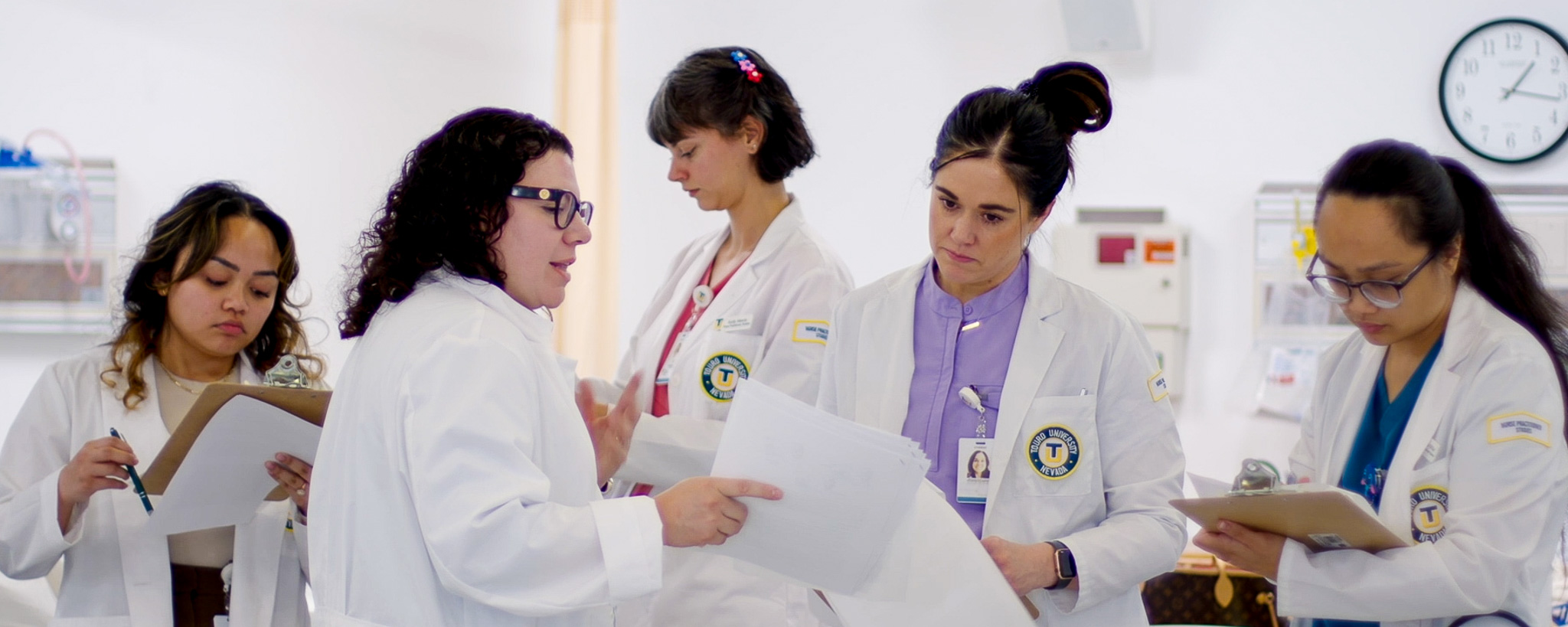 A faculty member reviews information on a chart with nursing students in the clinical simulation center.